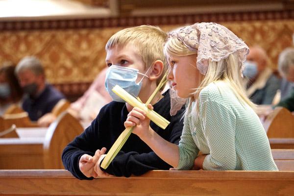 Nine-year-old Aidan Geiselhart and his 6-year-old sister Anna, members of Christ the King Church in Little Rock, listen during Palm Sunday Mass at the Cathedral of St. Andrew March 28. (Malea Hargett photo) 