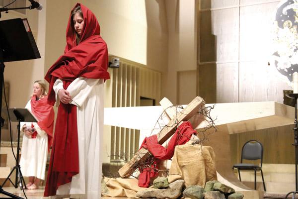Ellie Rockers (foreground) portrays Mary, mother of James and Joseph, while Mackenzie Ferguson narrates April 2 during Good Friday live Stations of the Cross at Christ the King Church in Little Rock. (Dwain Hebda photo) 
