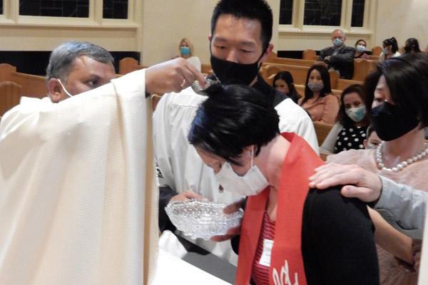 Father Ravi Rayappa Gudipalli, pastor of St. Mary Church in Hot Springs, baptizes Jennifer Nobles during Easter Vigil April 3. Six other people joined the Church by making a profession of faith and being confirmed. (James Keary photo) 