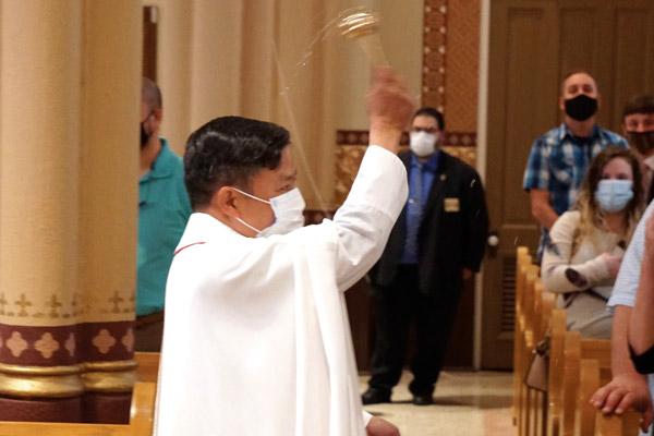 Father Jack Vu, rector of the Cathedral of St. Andrew in Little Rock, sprinkles holy water on parishioners after they renewed their baptismal vows during Easter Mass April 4. (Malea Hargett photo) 