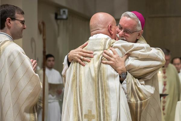 Bishop Anthony B. Taylor hugs newly ordained Father Norman McFall during his priestly ordination in 2016. The bishop and fellow priests hug the newly ordained during the sign of peace. (Bob Ocken photo, Arkansas Catholic file)