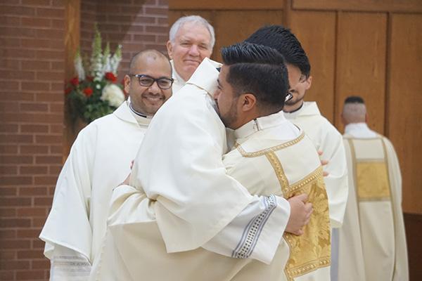 Close friend Deacon Omar Galván, who will be ordained a priest May 29, hugs Deacon Jaime Nieto as Deacon Emmanuel Torres, who will also be ordained a priest, smiles during the sign of peace. Galván and Torres also vested Nieto in his liturgical vestments during ordination Mass May 21. (Aprille Hanson Spivey photo) 