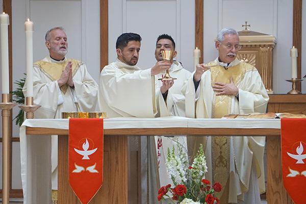 Jaime Nieto holds the chalice during the Liturgy of the Eucharist beside Anthony B. Taylor (right), Father Daniel Ramos and Msgr. Scott Friend, outgoing vocations director, during his diaconate ordination May 21 at St. Raphael Church in Springdale. (Aprille Hanson Spivey photo)