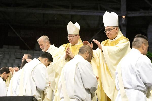 Msgr. Scott Friend (left), outgoing vocations director, Bishop Francis I. Malone of Shreveport and retired Archbishop J. Peter Sartain lay hands on the elect as a sign of presbyteral unity. (Bob Ocken photo)