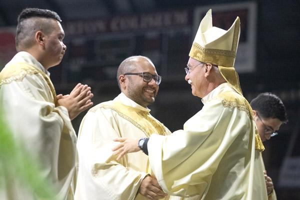 During the sign of peace, Bishop Anthony B. Taylor hugs Father Emmanuel Torres and the other new priests. (Bob Ocken photo)