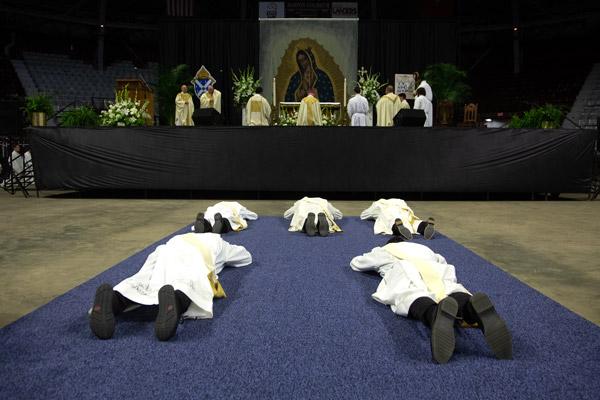 The five men seeking ordination lay prostrate on the floor of Barton Coliseum as a sign of surrender before God while the congregation sings the Litany of Saints. (Bob Ocken photo)
