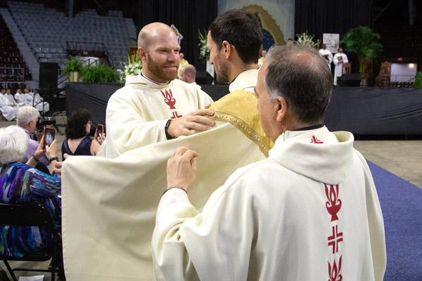 Father Joseph Friend of Conway and visiting priest Father Jim Mattaliano place the stole and chasuble on Father Ben Riley. (Bob Ocken photo)