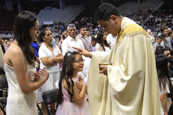 Father Omar Galván distributes Communion to his extended family who came from Fort Smith to celebrate his ordination. (Bob Ocken photo)