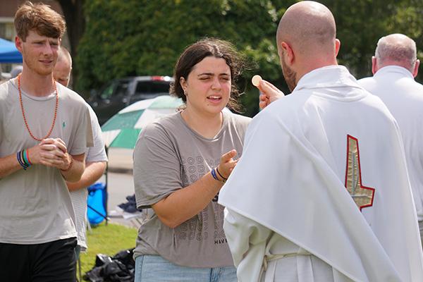 Rachel Ridgeway from Christ the King Church in Little Rock and Andrew Lee from St. John Church in Russellville receive Communion from Father Patrick Friend. (Malea Hargett photo) 