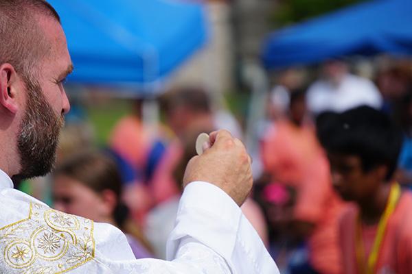 Father Jeff Hebert distributes Communion during Mass at Glory on the Grounds June 6. (Malea Hargett photo) 