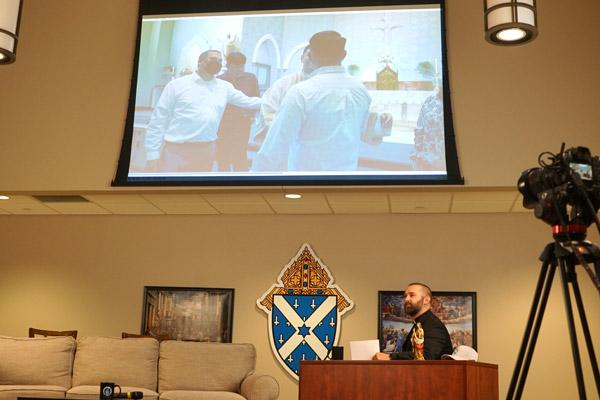 A video introducing the five new diocesan priests is played during Taste of Faith as Father Jeff Hebert listens. (Malea Hargett photo)