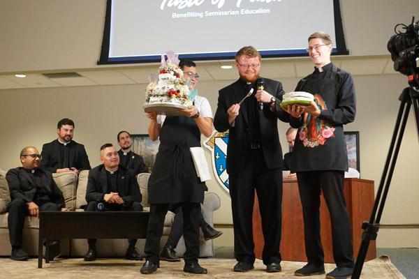 Seminarian Cody Eveld (center) pulls a fork out of his coat pocket to taste cakes baked by Hong Nguyen (left) and John Paul Hartnedy. (Malea Hargett photo)