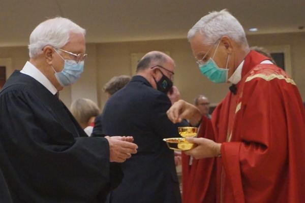 Jim Hamilton, retired North Little Rock District Court judge, accepts the Eucharist from Bishop Anthony B. Taylor. (Chris Price photo) 
