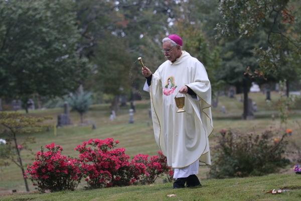 Bishop Anthony B. Taylor sprinkles holy water on the gravesites of departed priests as the congregation prays the rosary as they walk through Calvary Cemetery following the All Souls Mass in Little Rock Nov. 2. (Photo Chris Price)