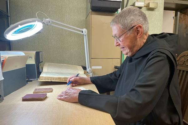 Father Jerome Kodell looks over a 1930s copy of the “School Children’s Prayerbook and Missal” Feb. 2 in the Subiaco Abbey archive room. The prayer book, created by the late Benedictine Father Lawrence Hoyt, had been missing from the archives. (Father Elijah Owens photo)