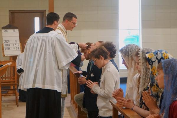 Father Jared McCambridge, FSSP, pastor of St. John the Baptist Church in Cabot, distributes holy Communion at the Mass following the dedication of the parish's new sanctuary. During the traditional Latin Mass, holy Communion is always received on the tongue and, for those physically able, while kneeling.