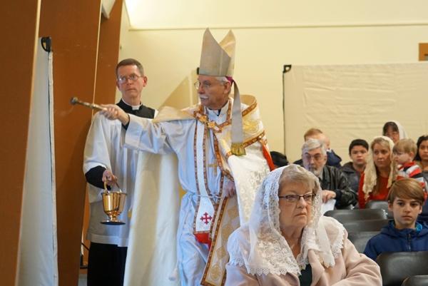 Bishop Anthony B. Taylor, assisted by Father Jared McCambridge, FSSP, pastor of St. John the Baptist Church in Cabot, sprinkles holy water while dedicating the parish's new sanctuary, March 19.
