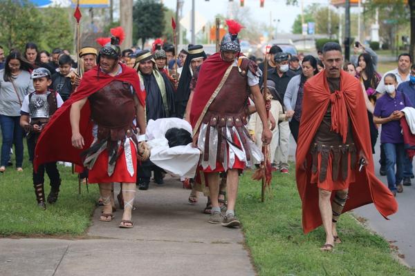 Pilate, played by Hugo Arias, leads Roman soldiers who carry the dead body of Jesus, played by Leonardo Lugo Flores, in procession with other reenactors and with members of the audience from MacArthur Park in Little Rock across East Ninth Street to St. Edward Church to be laid in the tomb. Chris Price photo.
