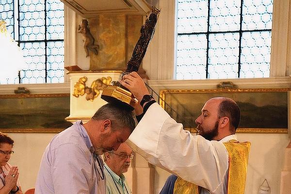Father William Burmester, spiritual director for the second pilgrimage, blesses John Nabholz of Conway July 1 with a 400-year-old Marian statue following Mass in Munich.