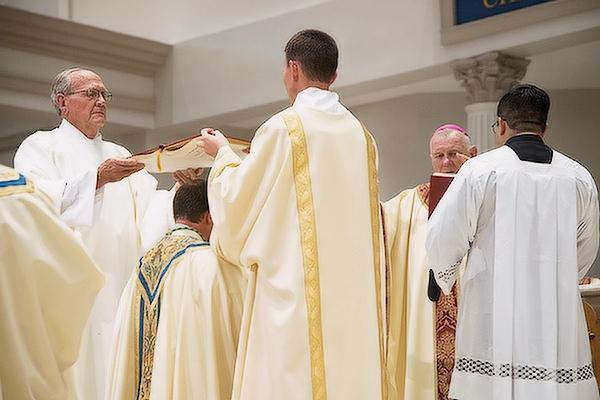 Deacons Tom and Jason Pohlmeier, father and brother of Bishop-elect Erik T. Pohlmeier, hold open the Book of the Gospels over his head during the Prayer of Ordination.