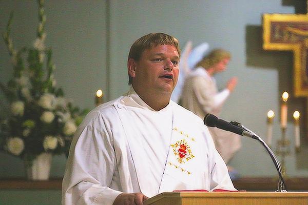 Deacon Christopher Dorer, who was ordained June 11, reads the Gospel at the opening Mass celebrating the 100th anniversary of St. Francis of Assisi Church in Little Italy. The parish celebrated its centennial Aug. 5-7. (Chris Price photo)