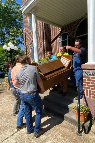 Organist and jack-of-all-trades Seth Smithee (top right) directs members of St. John the Baptist Church in Engelberg as they move the old organ out of the church.