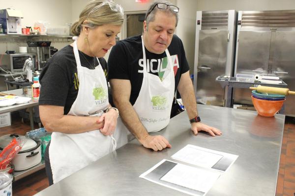 Janie and Mike Kelley read copies of recipes from Mike’s family cookbook before Italian Club members arrive March 2 at the Christ the King in Little Rock Family Life Center. (Katie Zakrzewski)