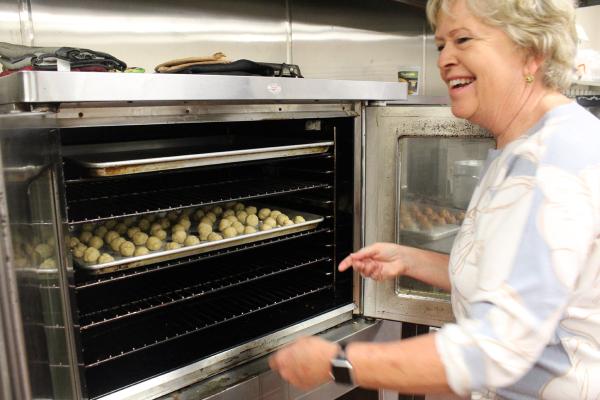 Sherry Simon smiles as she puts a tray of spice cookies into the oven of the Family Life Center at Christ the King in Little Rock March 2. The spice cookies, called “Connie’s Spice Cookies” in Mike Kelley’s family cookbook, contain ingredients such as cloves and vanilla. (Katie Zakrzewski)