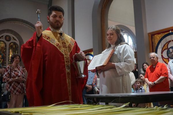 Father Daniel Wendel (photo on right), associate pastor at St. Joseph Church, blesses palms in the baptistry while altar server Abby Crowder, 13, holds the Roman Missal during Palm Sunday Mass March 23. (Aprille Hanson Spivey)