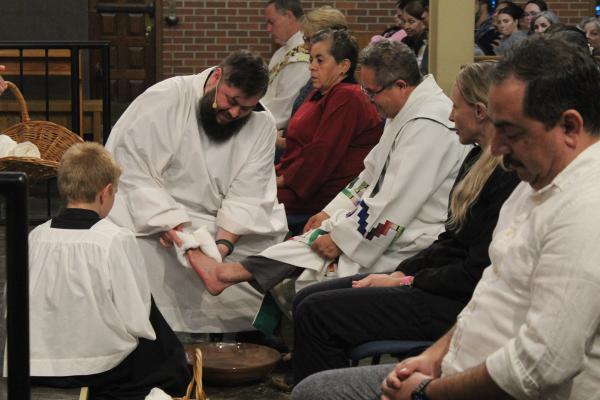 Father Luke Womack (center left) and Deacon Marcelino Luna (center right) share a laugh as Father Womack washes Deacon Luna's feet on Holy Thursday at Our Lady of Fatima Church in Benton March 28. (Katie Zakrzewski) 